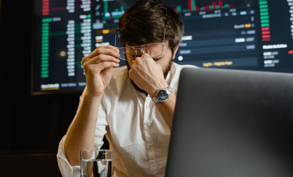 Man Rubbing Eyes Sitting In Front Of Laptop